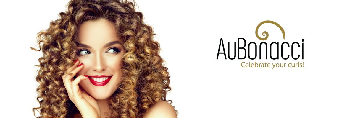 Woman with gorgeous golden brown curls wearing red lipstick blue eyes smiling with hand touching cheek looking over at AuBonacci Celebrate your curls logo